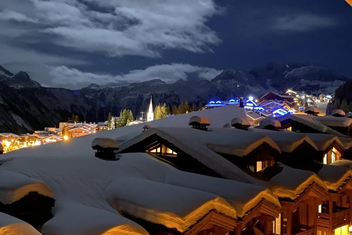 Balcony view of snow-covered village and mountains at night