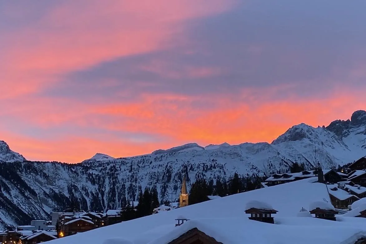 Ski village sunset view over snow-covered mountains and village rooftops