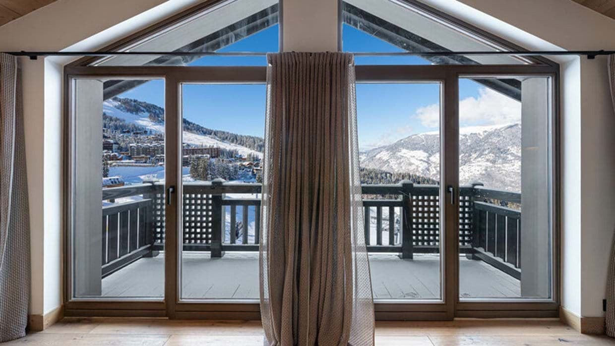 Floor-to-ceiling windows with private balcony access and ski resort views