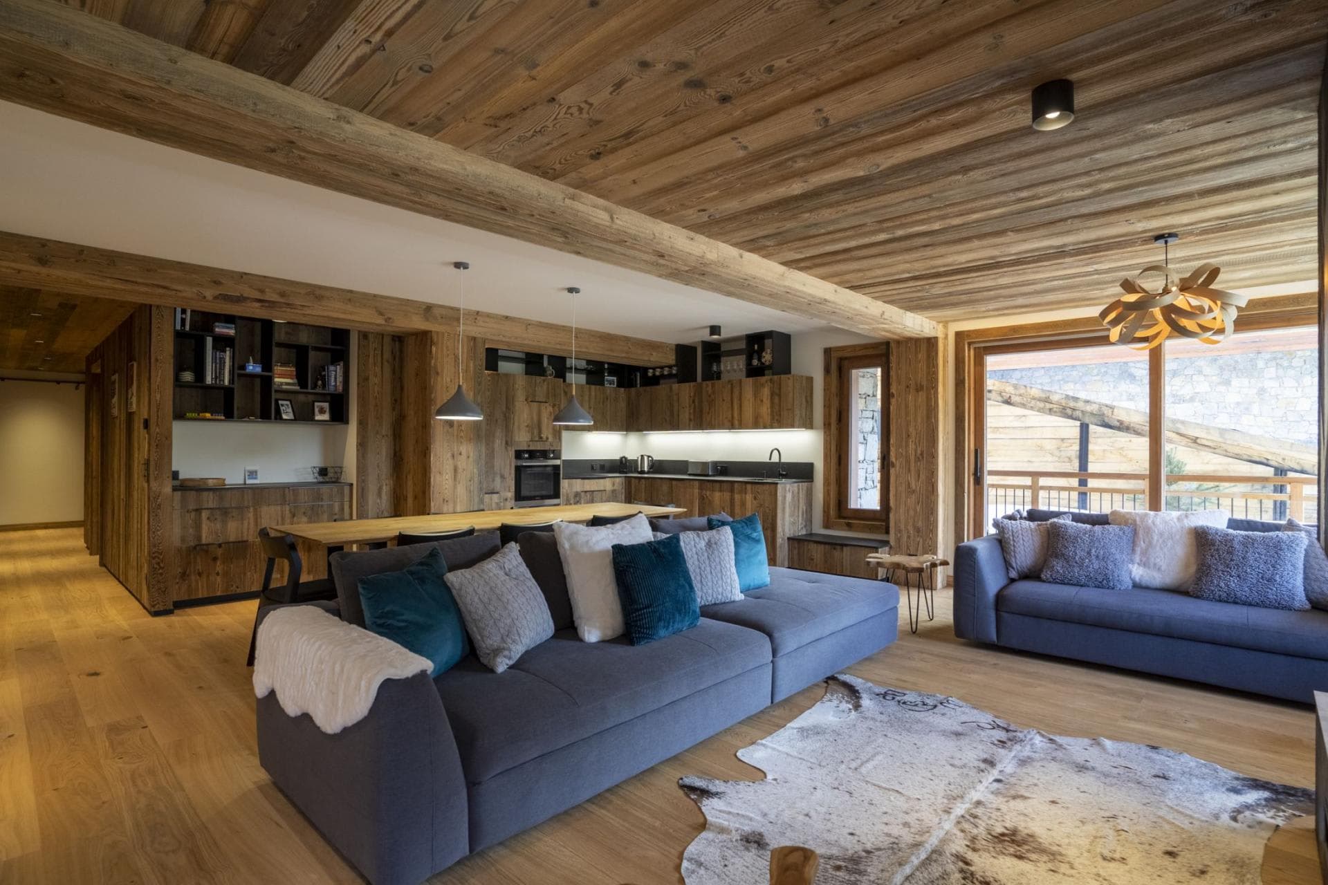 Open-plan living area with reclaimed wood ceilings and balcony access
