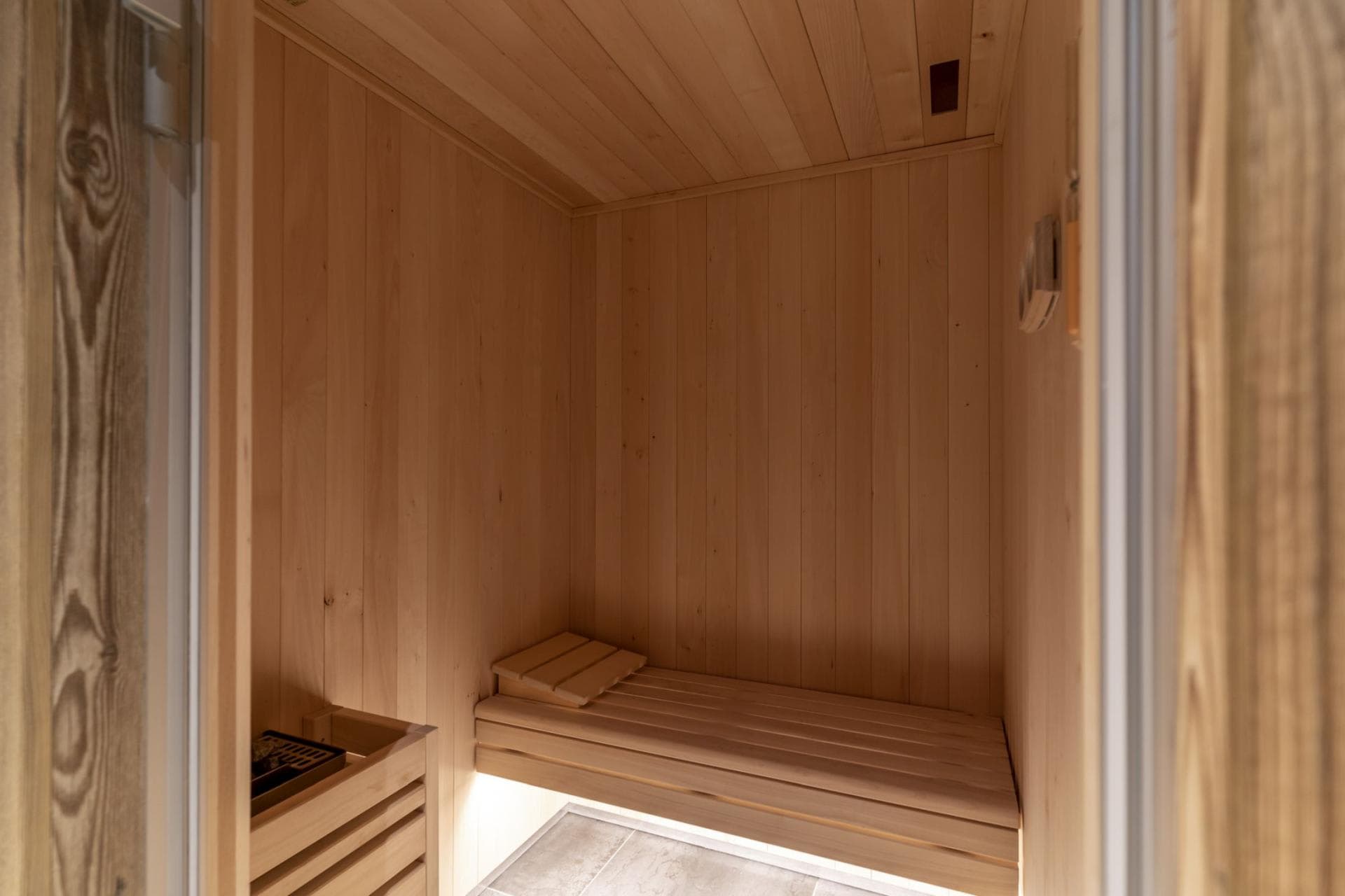 Private cedar sauna with electric heater and tiered wood bench