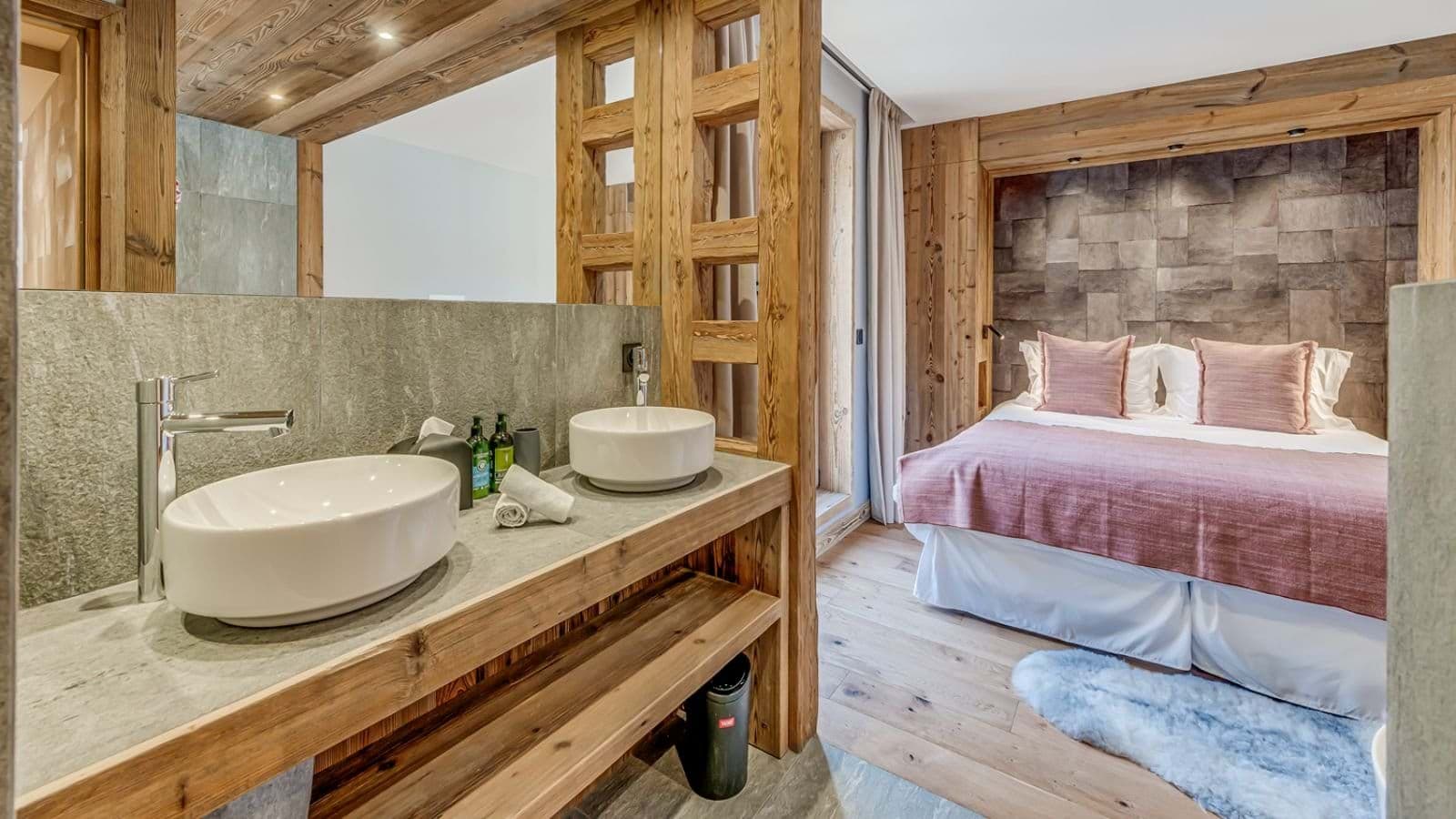 Ensuite bedroom featuring dual vessel sinks and king bed with reclaimed wood accents