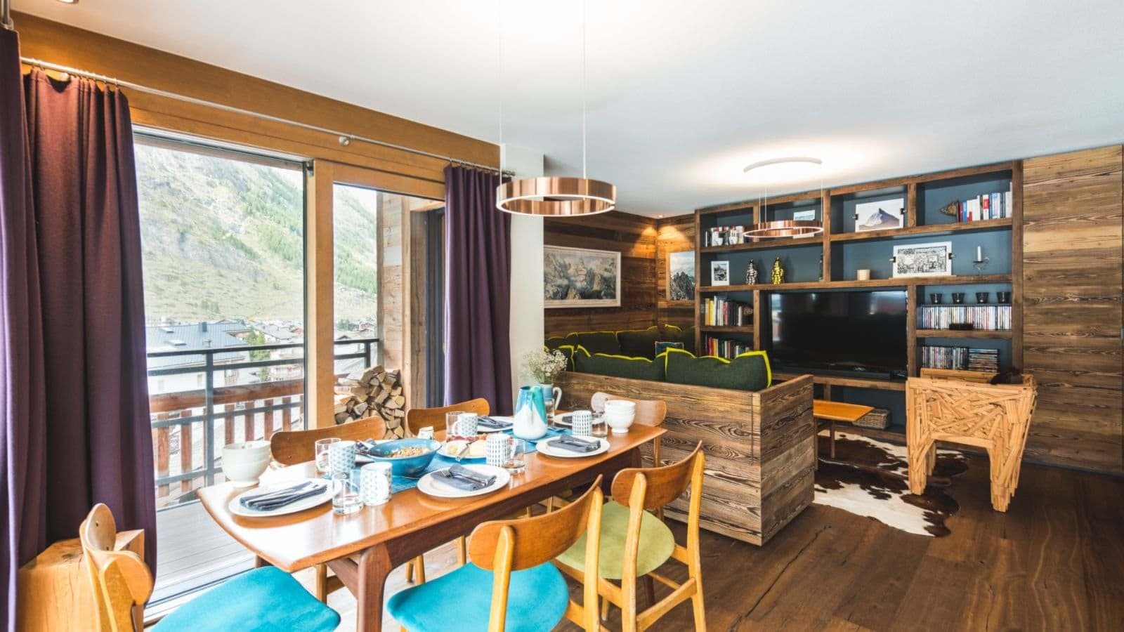 Open-plan dining and living area with mountain-view balcony and media library