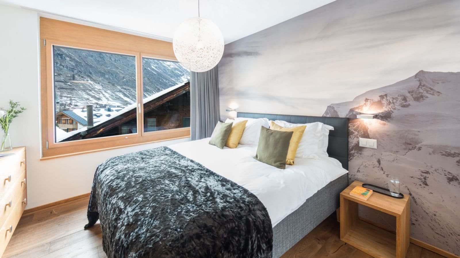Bedroom with mountain views and alpine mural behind king bed