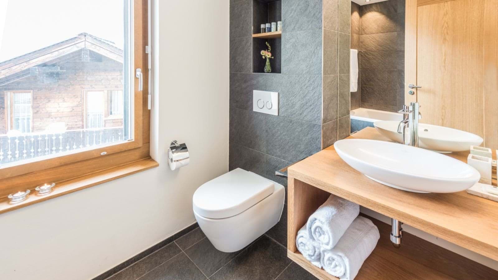 Bathroom featuring vessel sink, wall-hung toilet, and soaking tub