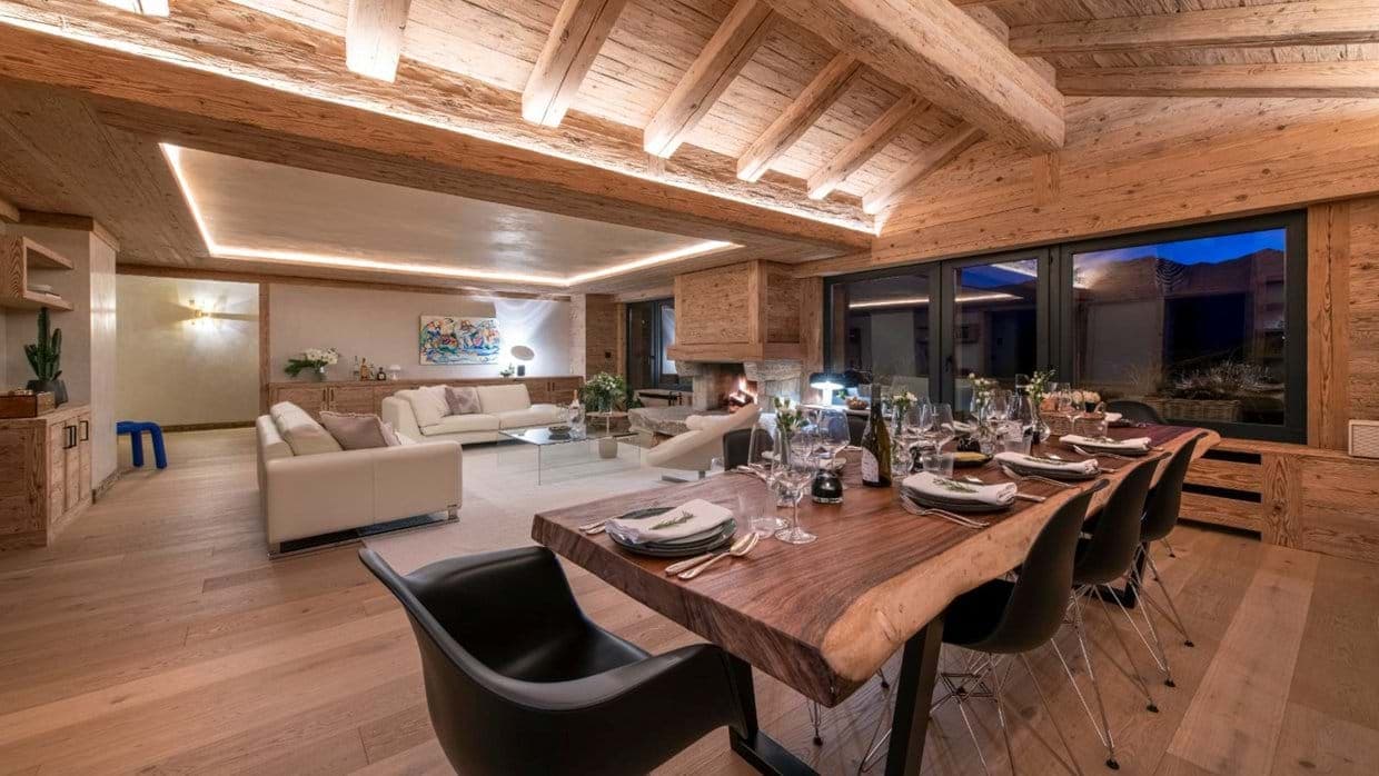 Open-plan living area with live-edge dining table seating 10 and wood-burning fireplace