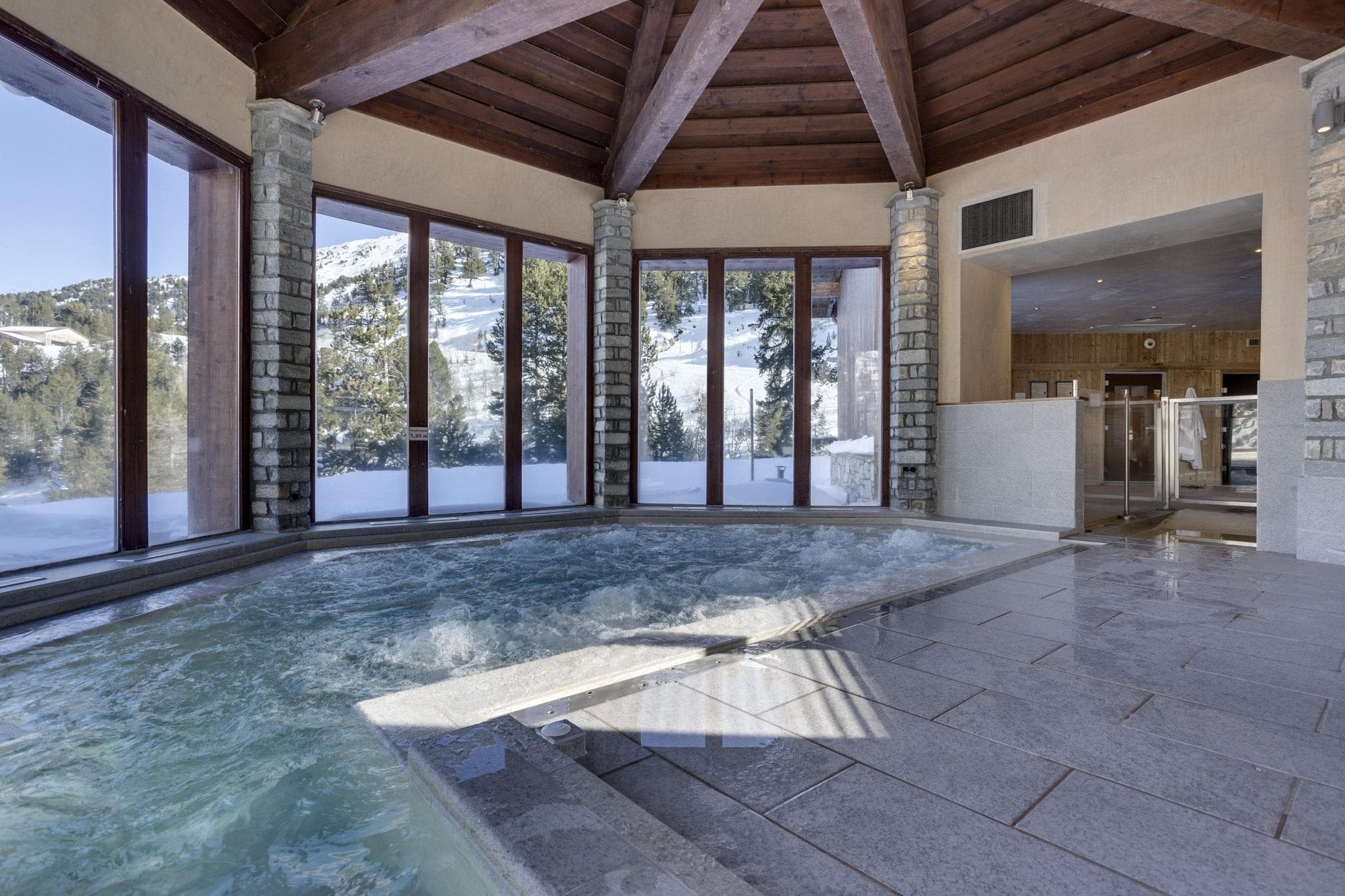 Indoor pool with panoramic mountain views and adjacent sauna