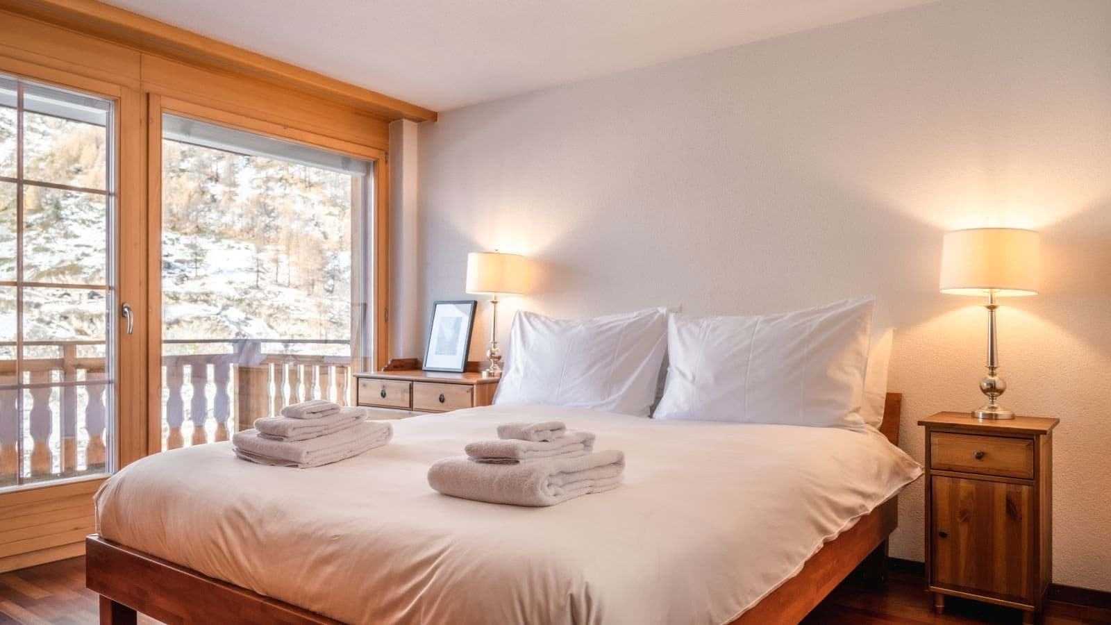 Bedroom with king bed and balcony access; snowy mountain view