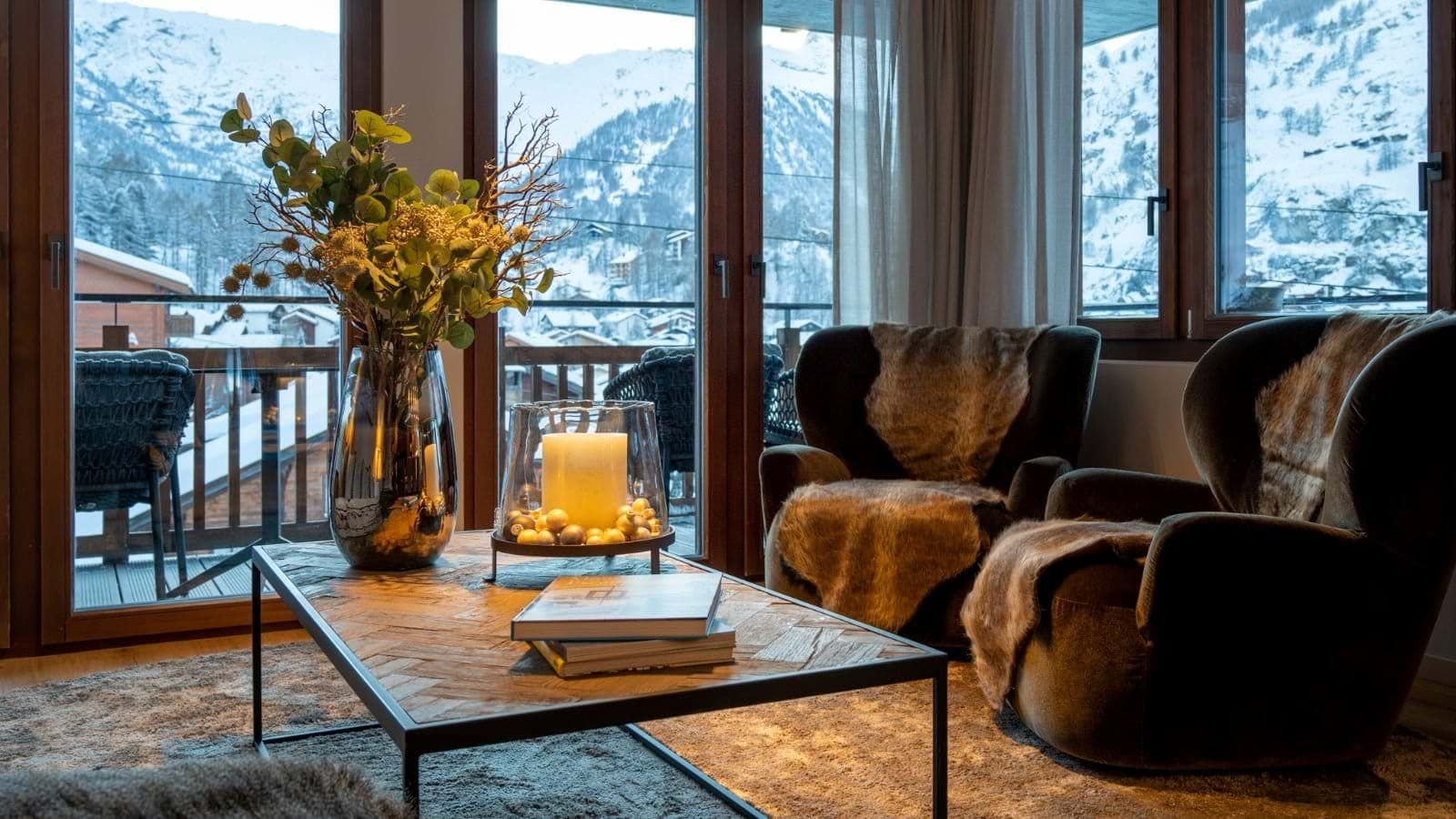 Living area with velvet armchairs and floor-to-ceiling mountain views