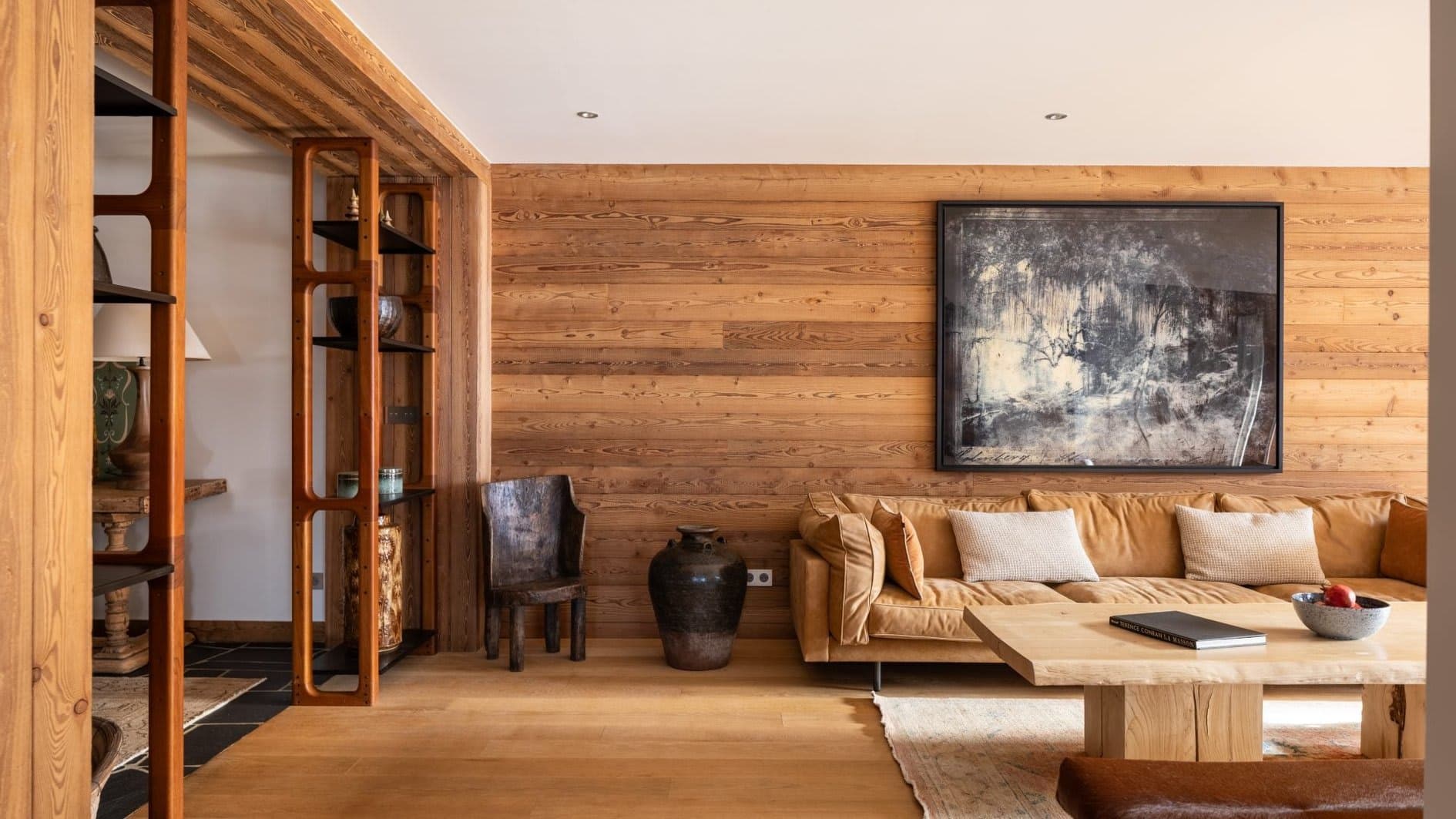 Living area with wood-paneled walls and floor-to-ceiling shelving divider