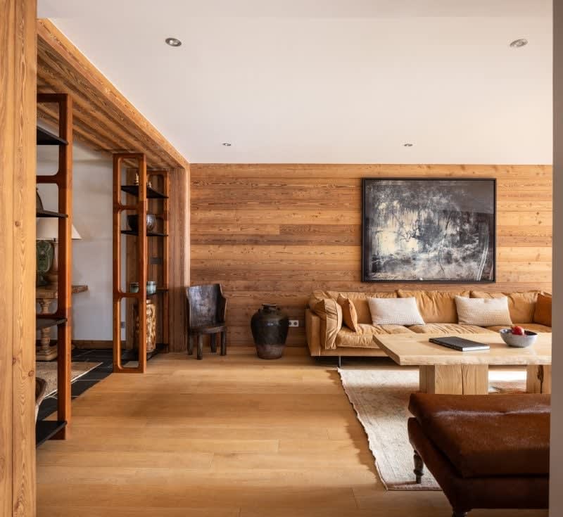 Living area with wood-paneled walls and open shelving divider