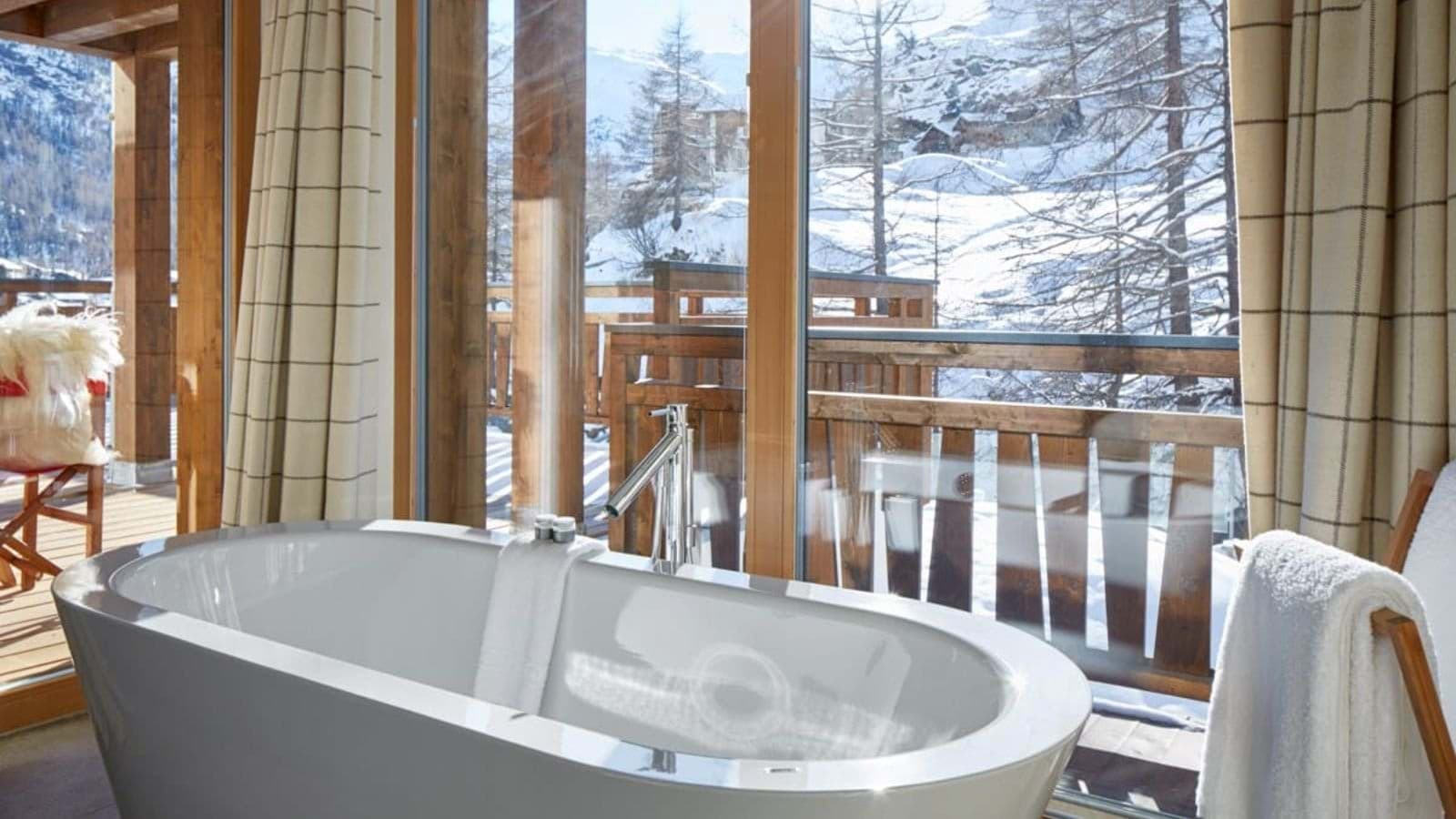 Freestanding soaking tub with floor-to-ceiling mountain and village views