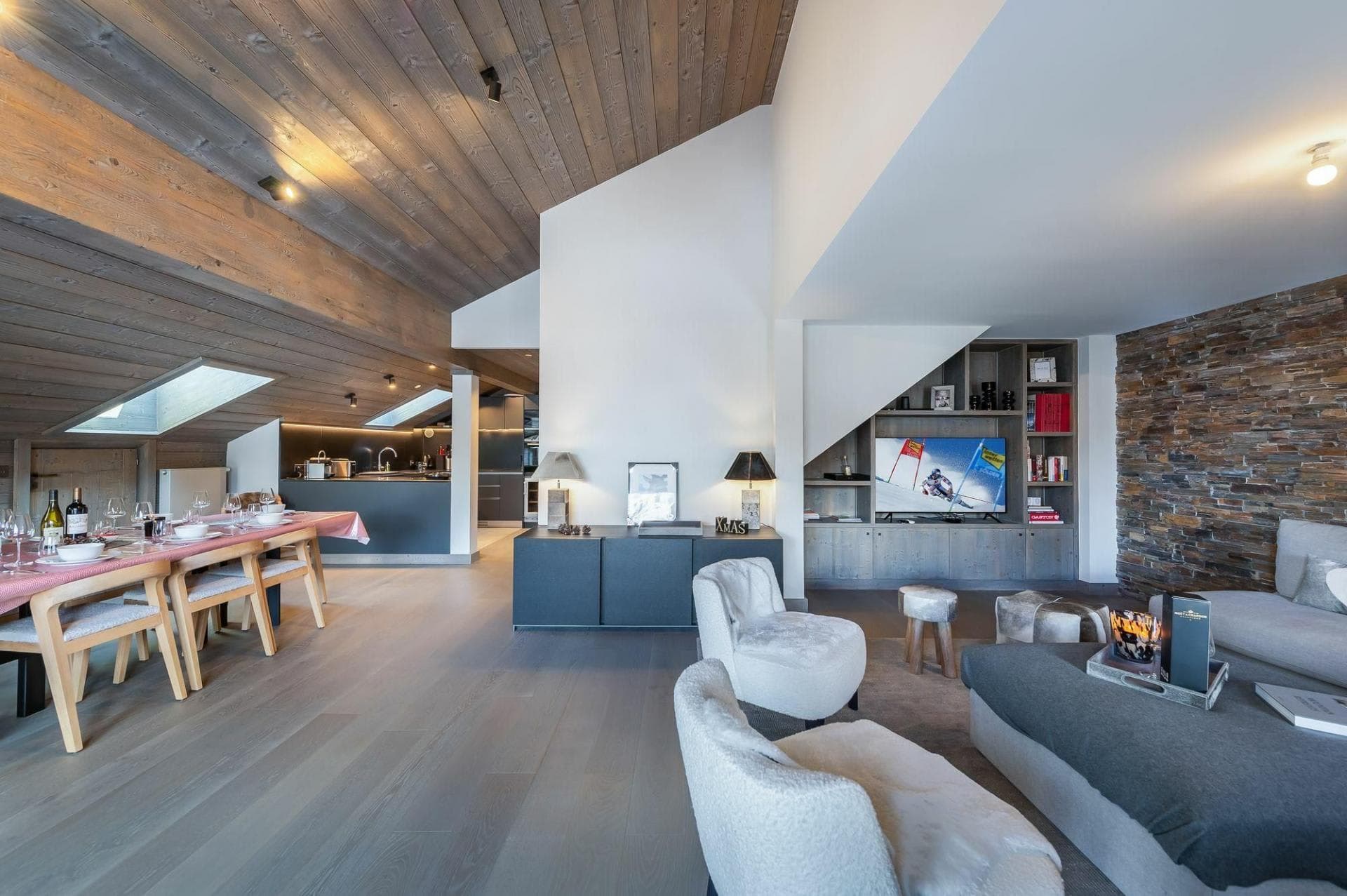 Open-plan living area featuring vaulted timber ceilings and stone accent wall