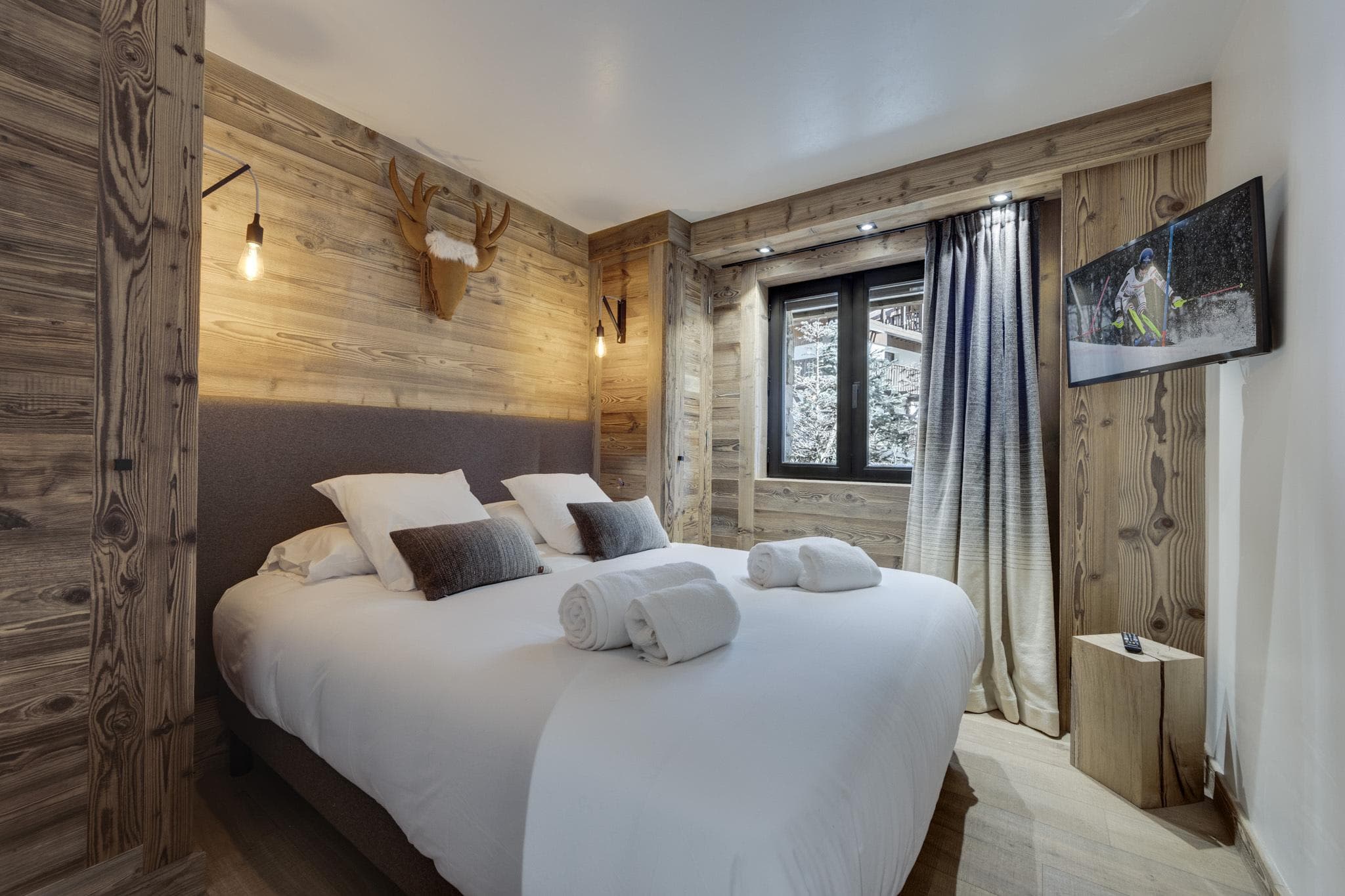 Wood-paneled bedroom with wall-mounted TV and king bed