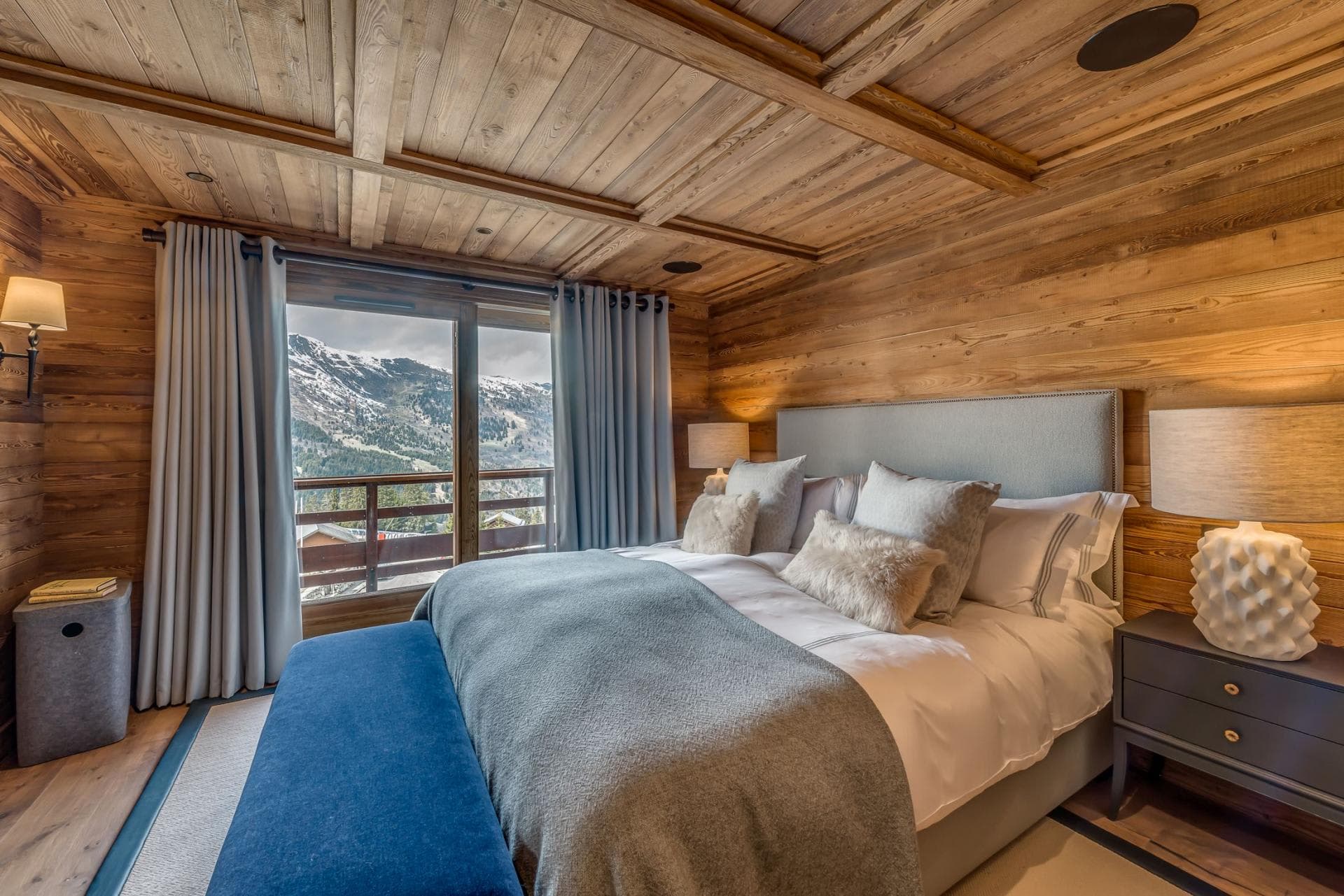 Wood-paneled bedroom with king bed and private mountain-view balcony