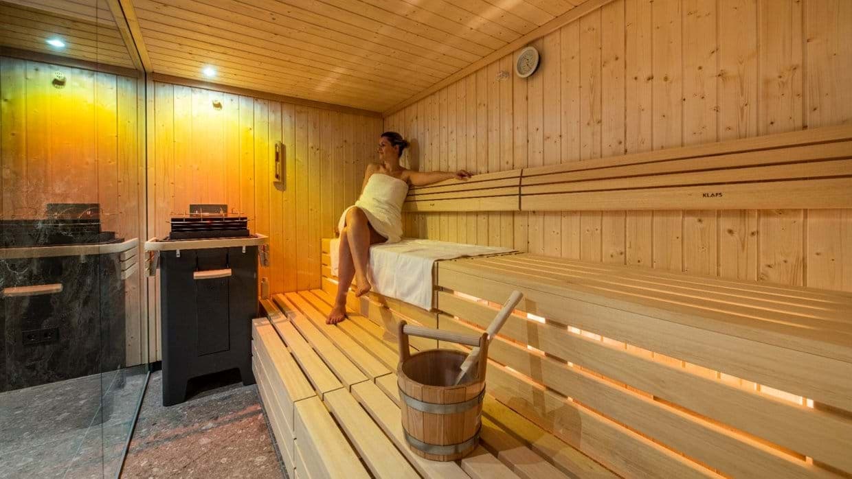 Indoor sauna with two-tier wood benches and integrated lighting