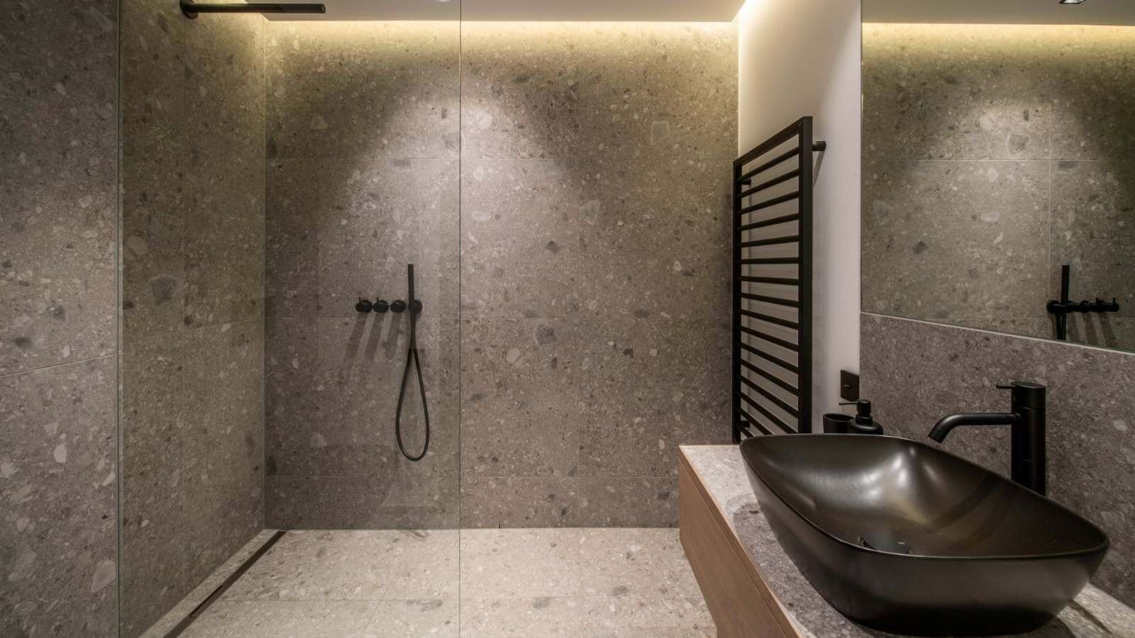 Bathroom with stone-tiled walk-in shower and heated towel rack