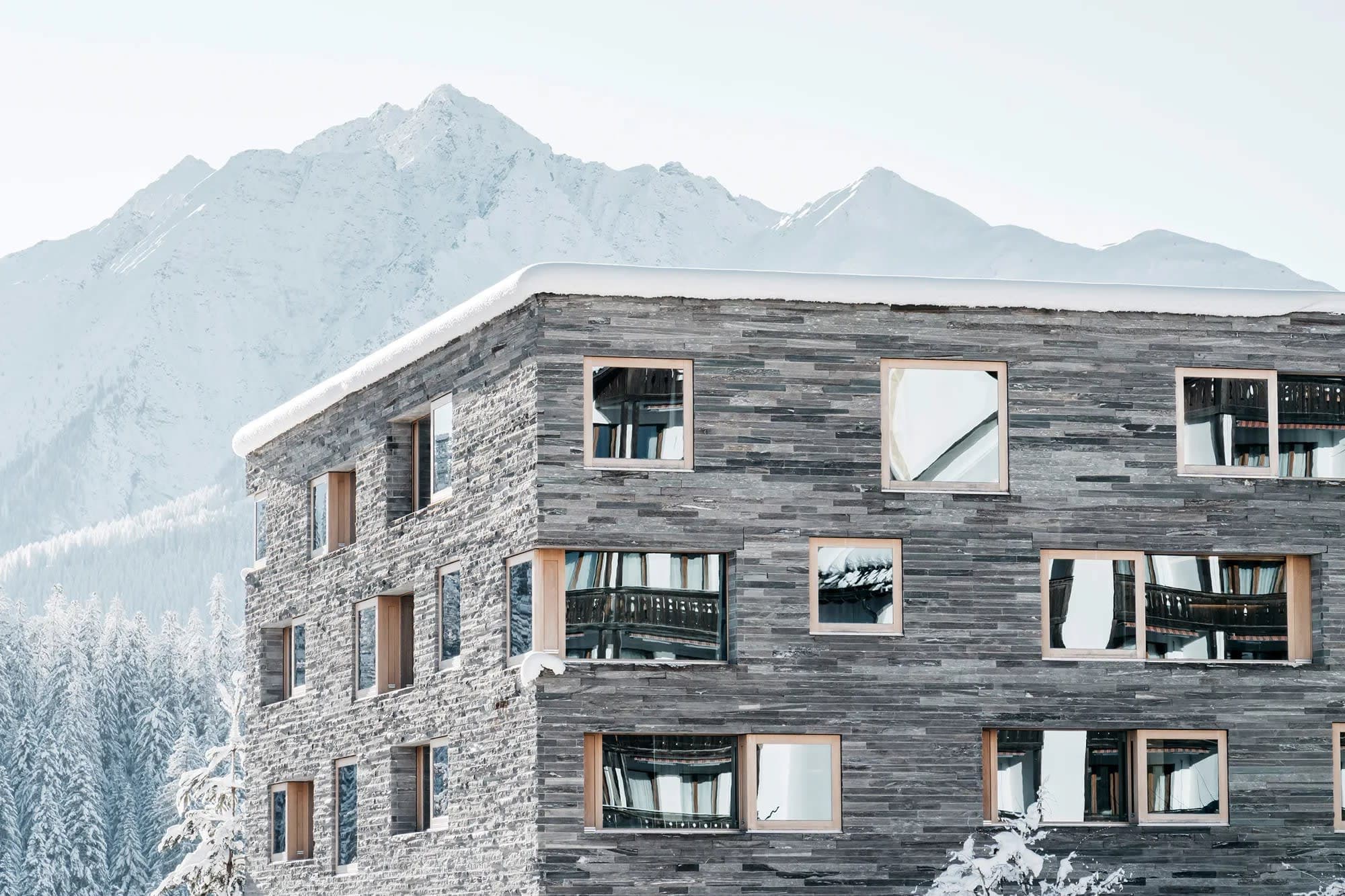 Stone facade exterior with alpine mountain views and snow-covered roof