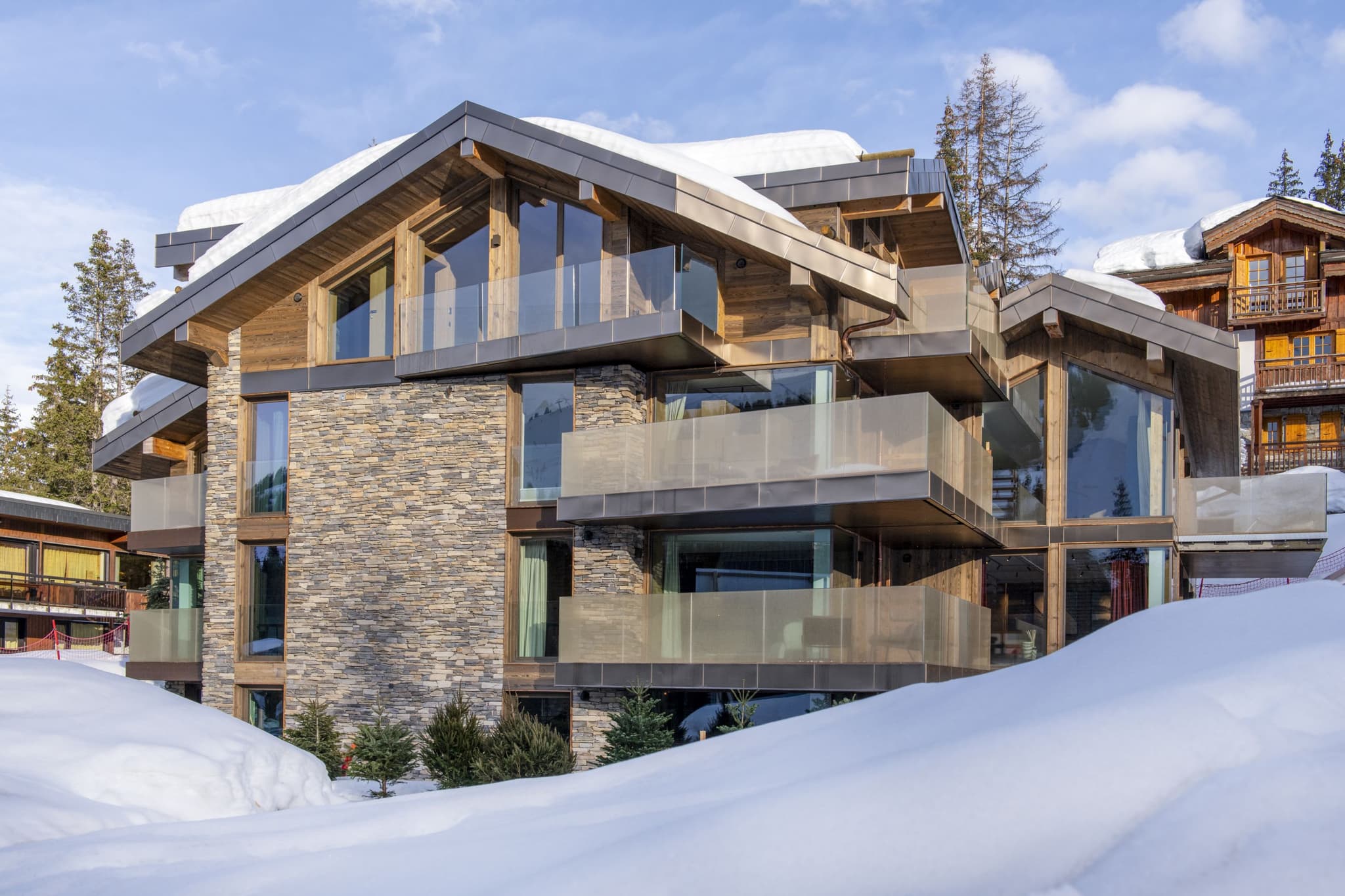 Ski-in chalets with stone masonry and private balconies overlooking the slopes