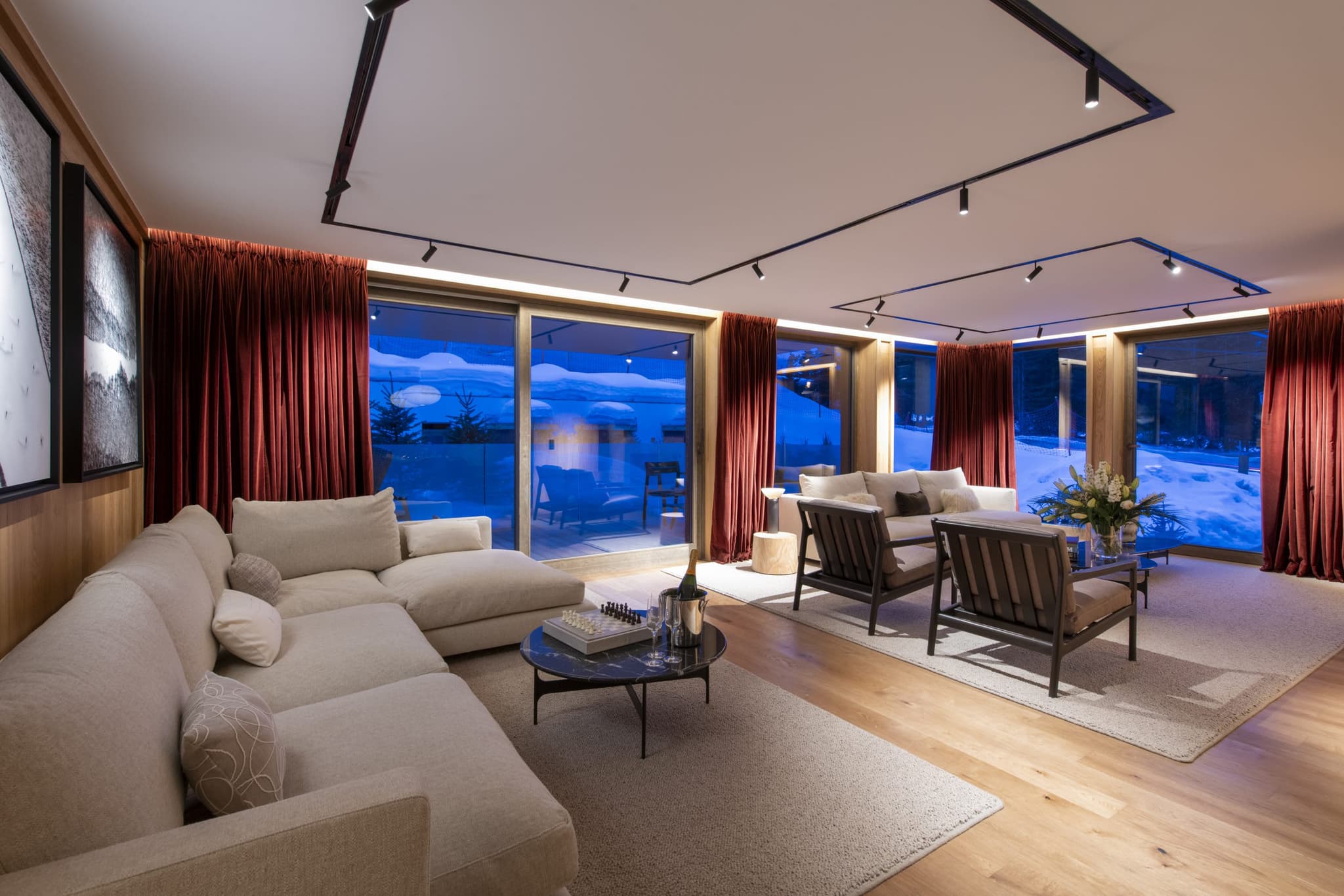 Living area with track lighting and floor-to-ceiling windows to snowy terrace