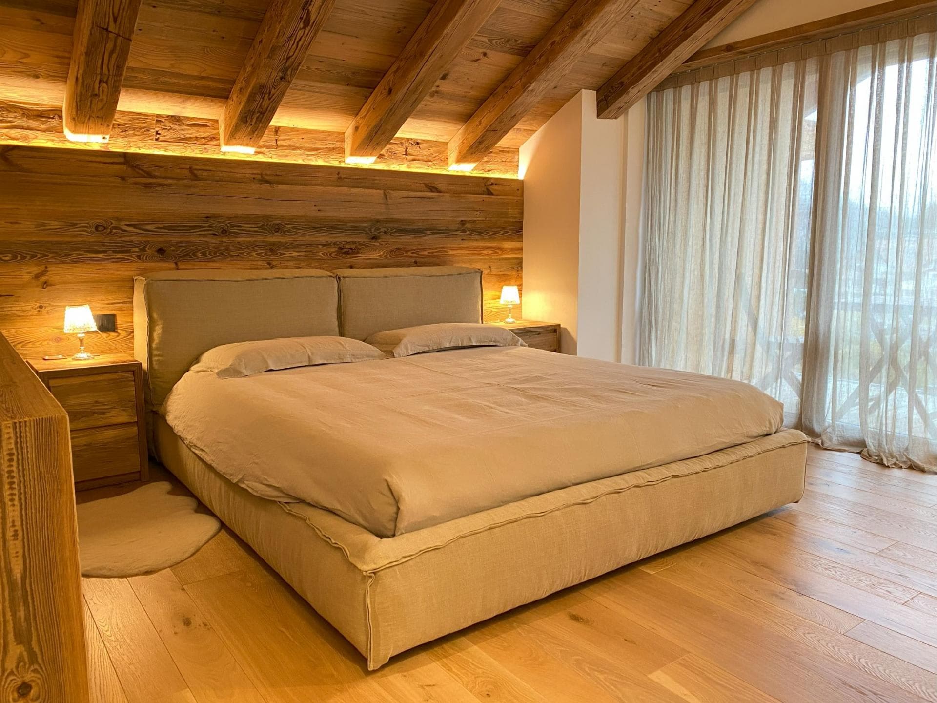 Primary bedroom with king bed, timber beams, and terrace access