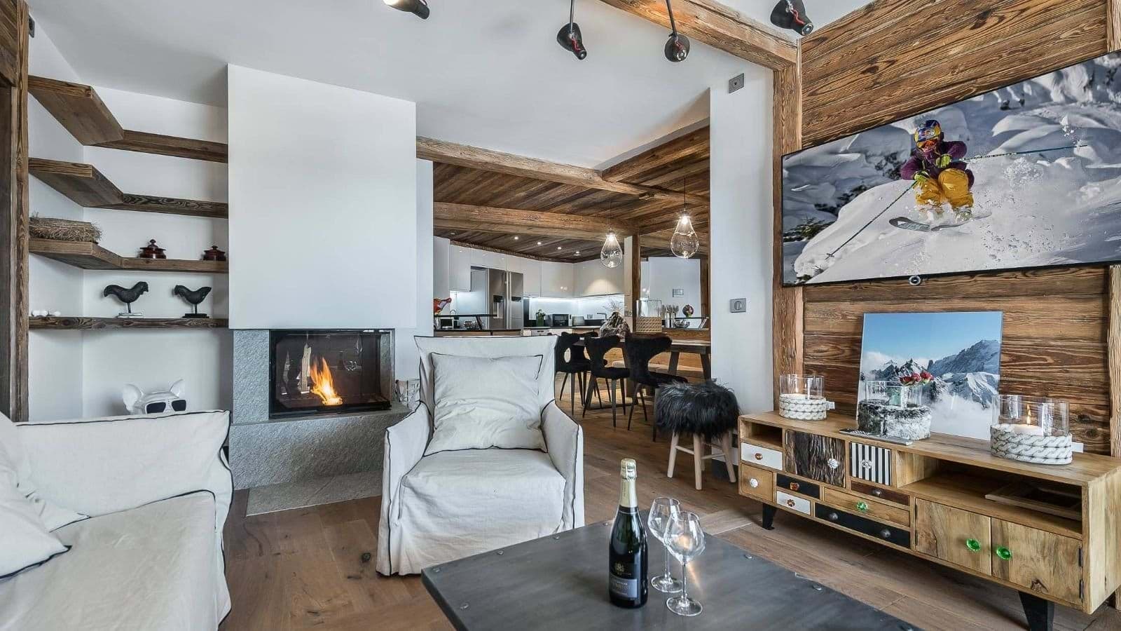 Open-plan living room with wood-beam ceiling, gas fireplace, and ski-themed TV wall