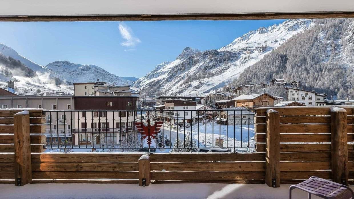Balcony with valley and Alpine views; metal railing frames snowy peaks