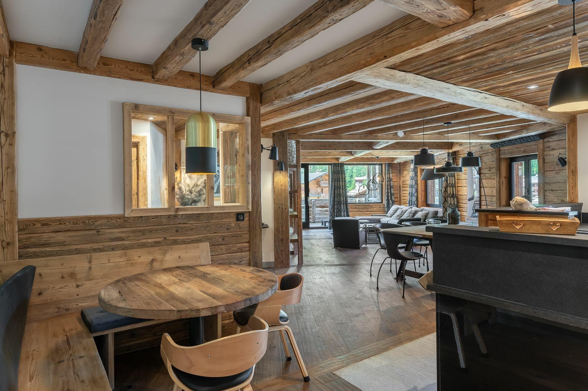 Open-plan living area featuring reclaimed wood beams and built-in breakfast nook