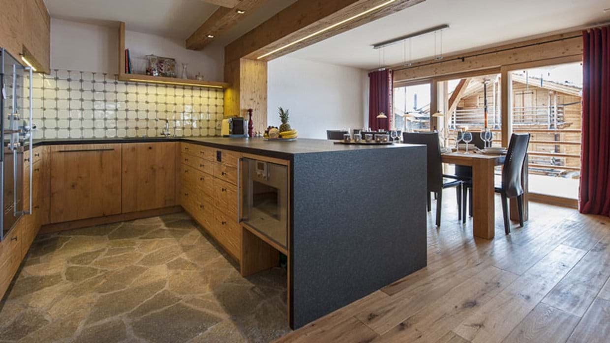 Open-plan kitchen with stone floors and dining table seating 8