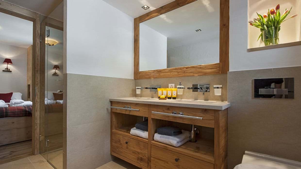 En suite bathroom with dual vanity and wood-framed mirror
