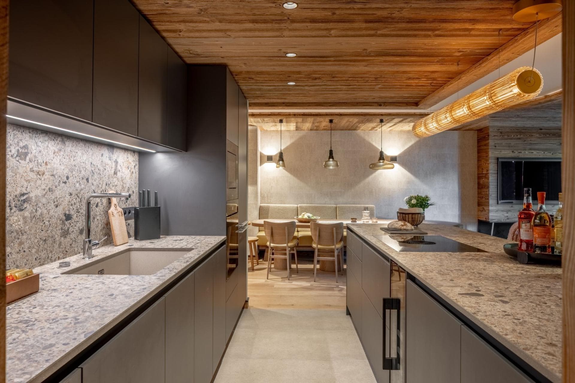 Kitchen with stone countertops, induction cooktop, and adjacent dining nook seating