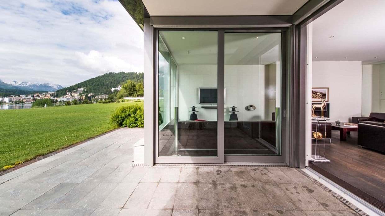 Stone patio with floor-to-ceiling sliding glass doors and mountain lake views