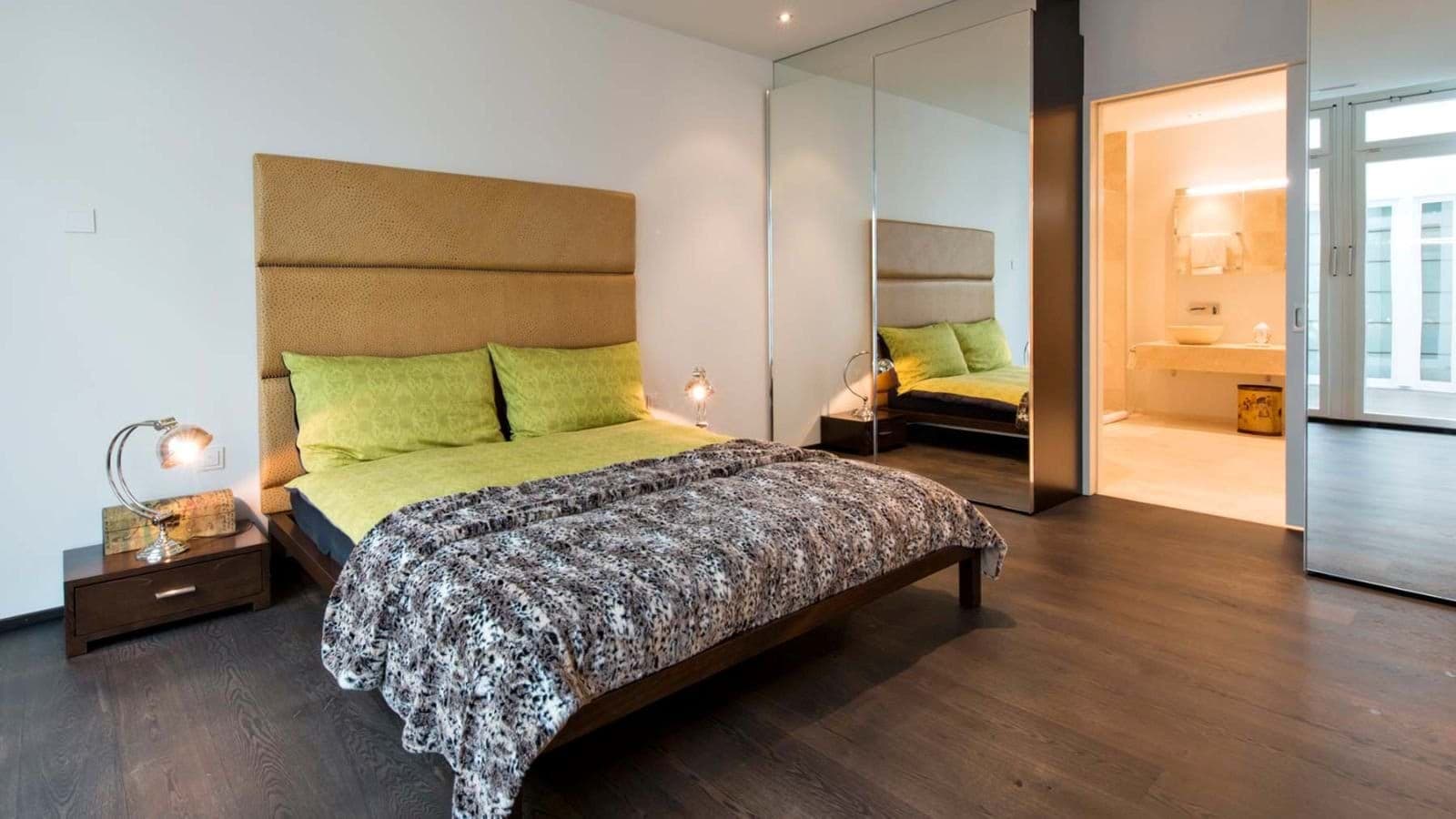 Primary bedroom with ensuite bathroom and mirrored floor-to-ceiling closets