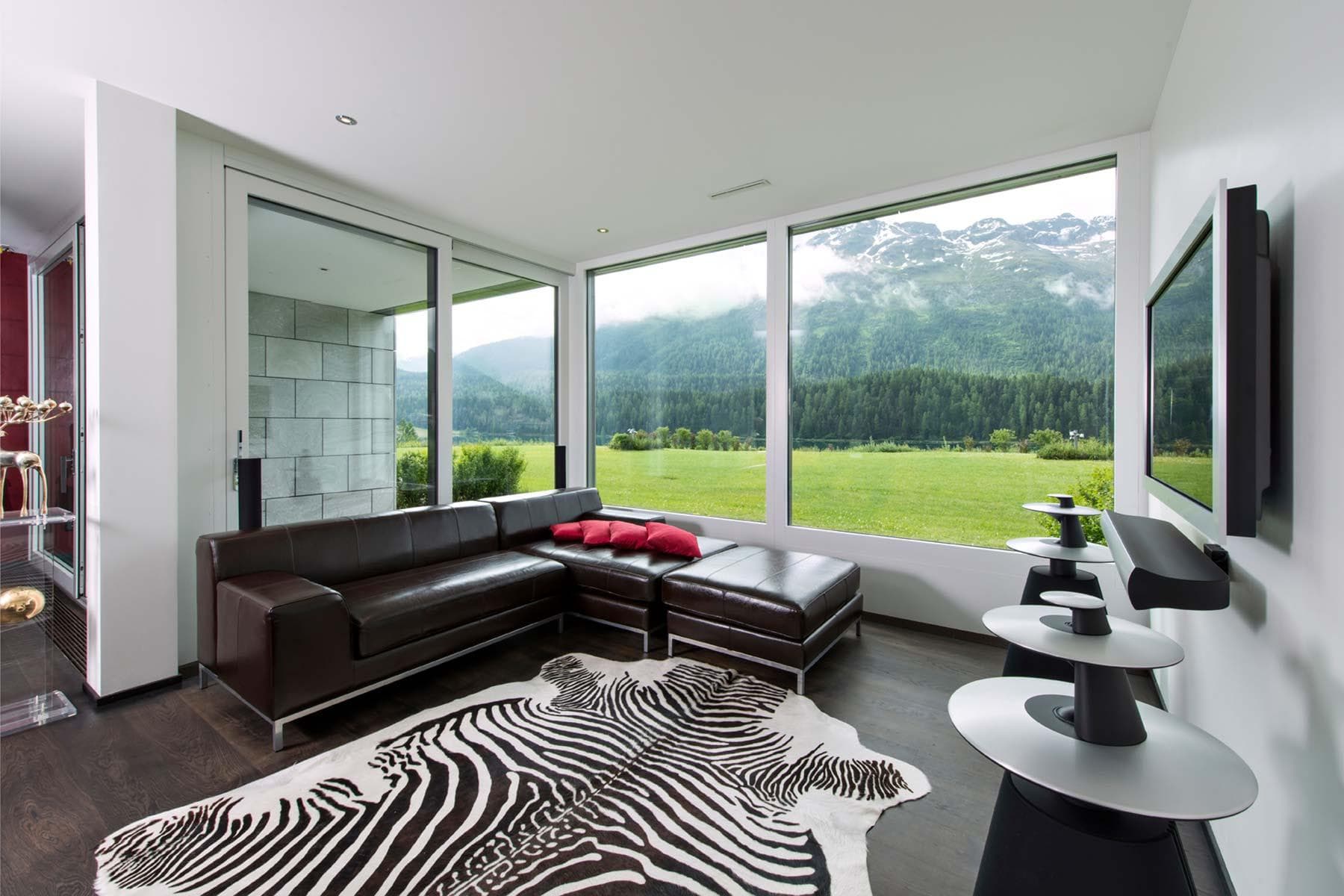 Living room with leather sectional and floor-to-ceiling mountain views