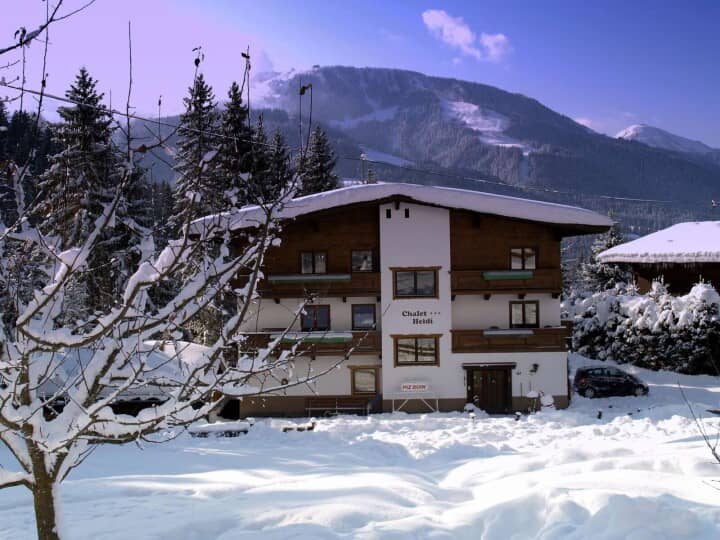 Chalet Heidi exterior with snow-covered grounds and ski slope mountain backdrop