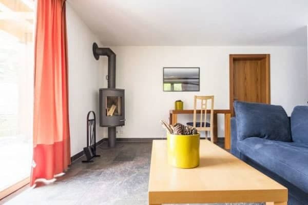 Living room with wood-burning stove, blue sofa, and dining table seating