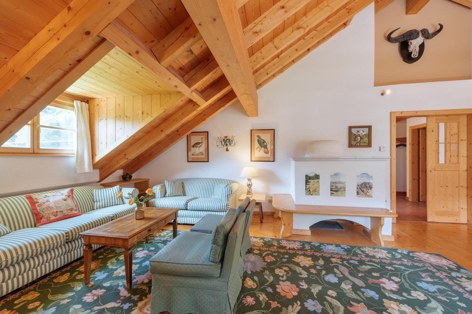 Living area with vaulted timber ceilings and traditional kachelofen tile stove