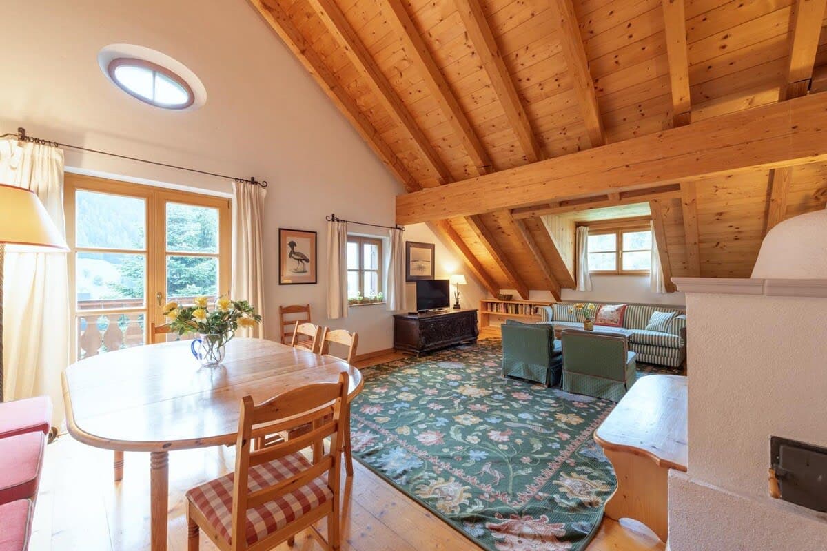 Open-plan living area with vaulted timber ceilings and balcony access