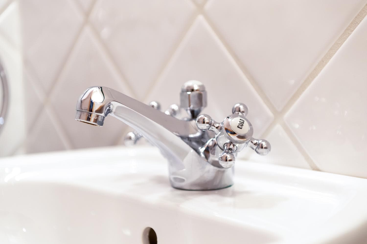 Bathroom sink with vintage-style chrome cross-handle faucet