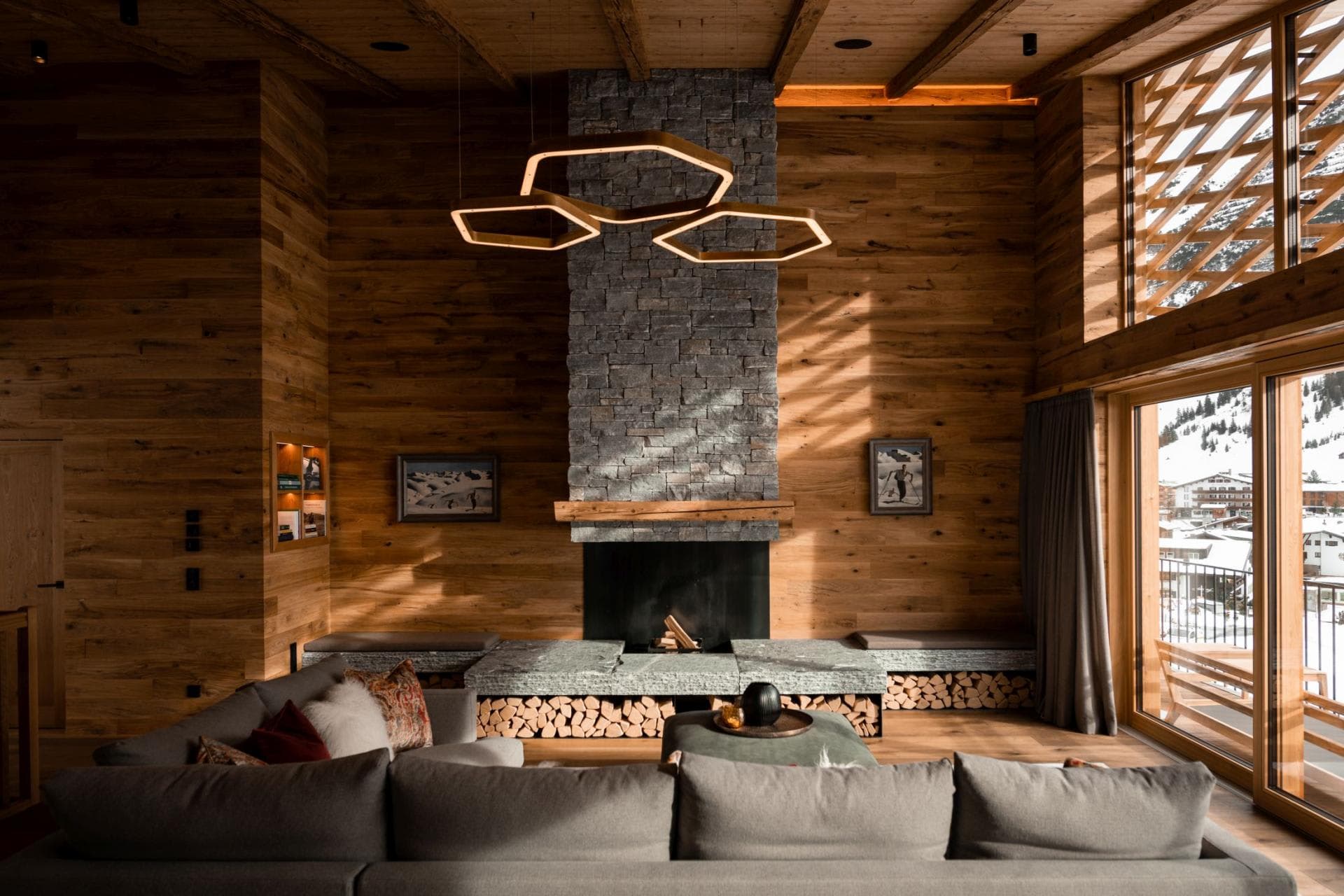 Living room with linear fireplace, neon pendant lights, and valley views through floor-to-ceiling glass doors