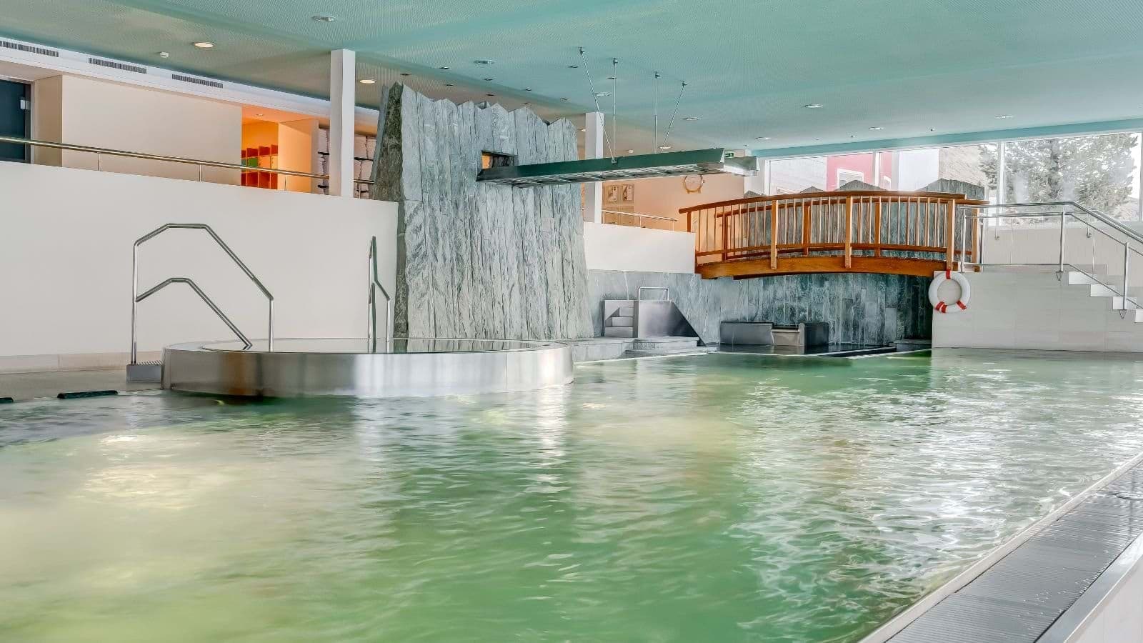 Indoor heated pool with integrated hot tub and waterfall feature