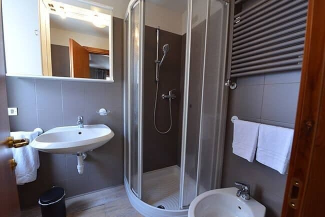 Bathroom with walk-in corner shower, bidet, and heated towel rack