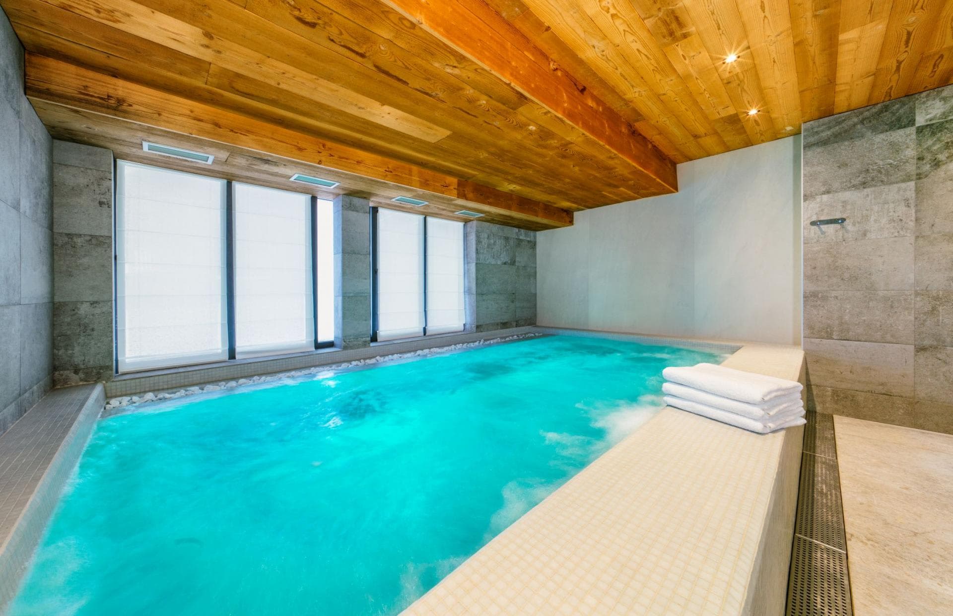 Indoor swimming pool with integrated jacuzzi jets and timber ceiling