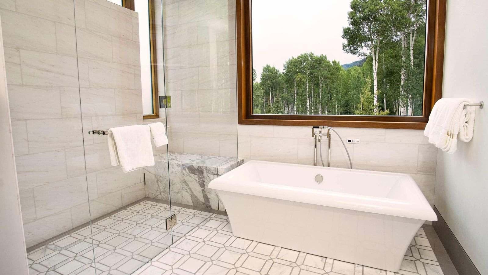 Bathroom with soaking tub, walk-in shower, and forest views