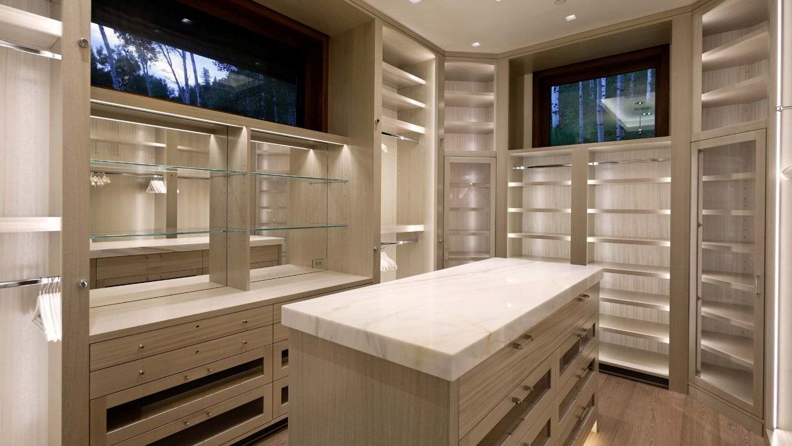 Walk-in closet with marble island, integrated lighting, and clerestory windows