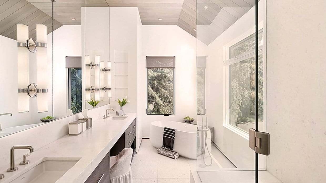 Primary bathroom with dual vanity, freestanding soaking tub, and glass shower