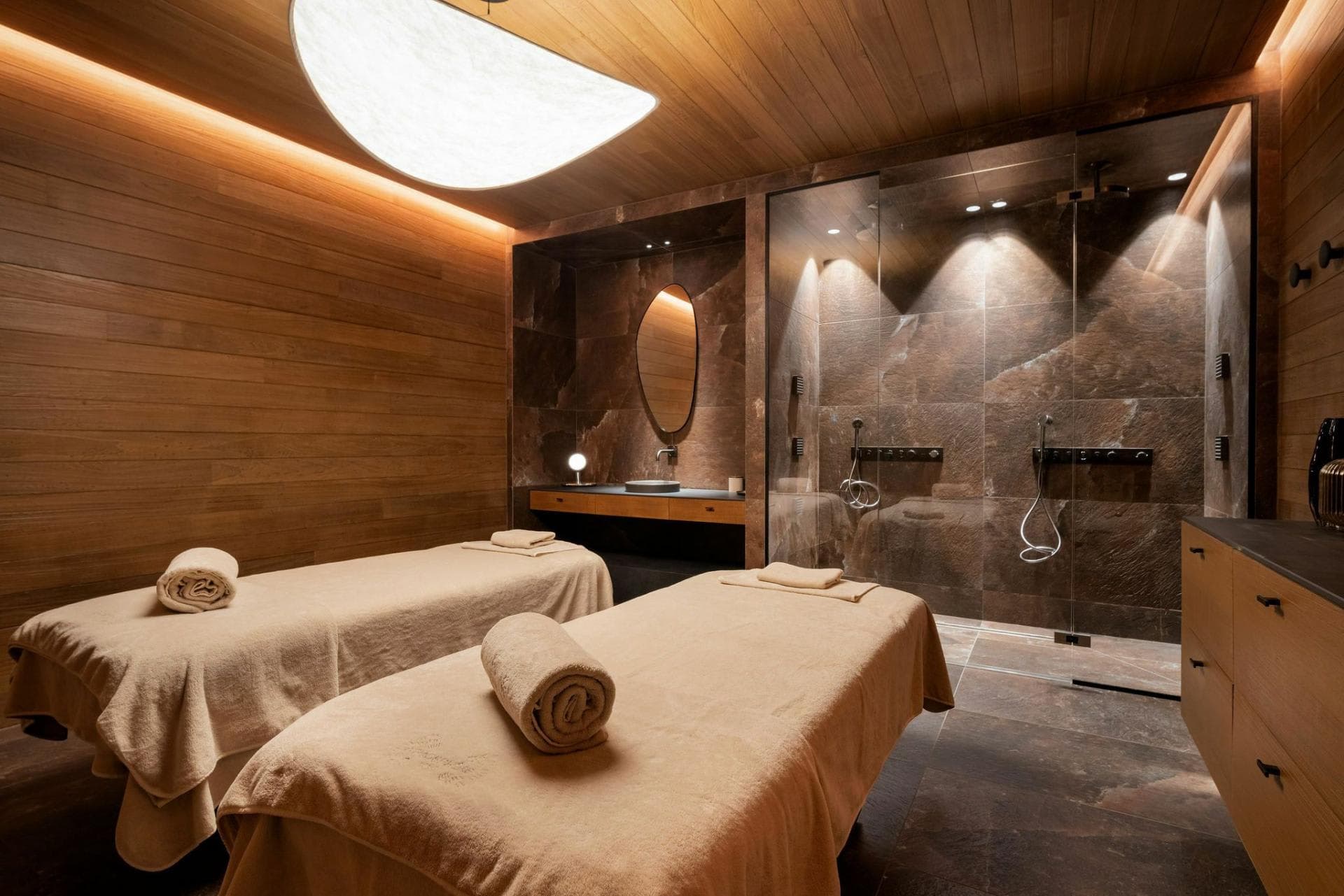 Private spa suite with dual massage tables and stone-clad walk-in shower