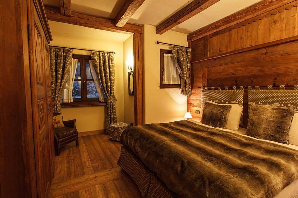 Bedroom with king bed, exposed timber beams, and reading chair nook