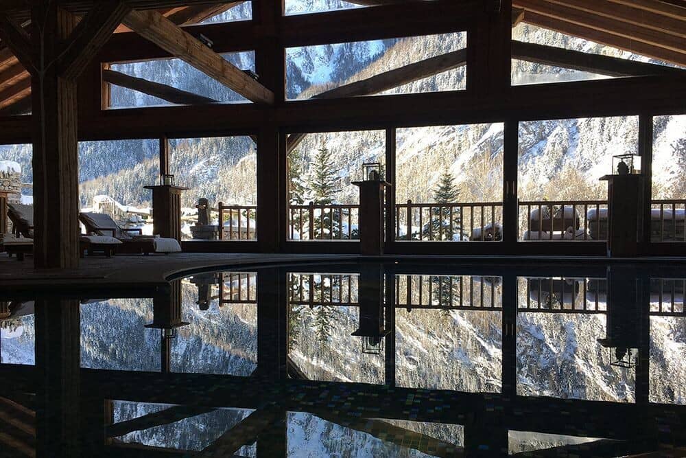 Indoor swimming pool with floor-to-ceiling mountain views