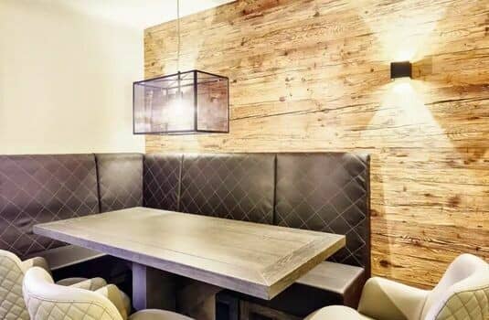 Dining nook with banquette seating and reclaimed wood feature wall